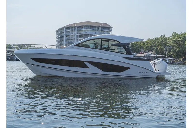 Slide: The Image of 2026 Beneteau Flyer 10 Sport Top boat on water, modern design, building in background. - 3