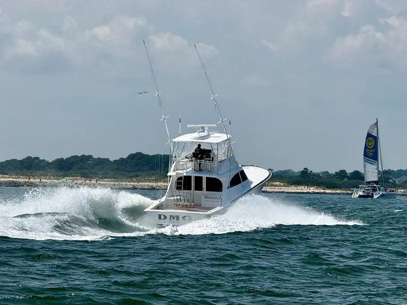 Slide: The Image of A 2027 Viking 50 Billfish speeds through the water, with a sailboat in the background. - 1
