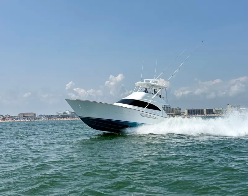 The Image of A 2027 Viking 50 Billfish speeds across the water, with a cityscape in the background. - 0