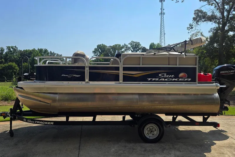 The Image of 2025 Sun Tracker Bass Buggy 16 XL Select pontoon boat on trailer, outdoors. - 0