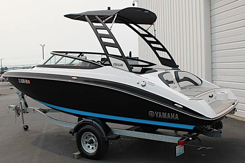 Slide: The Image of 2022 Yamaha Boats 195S on trailer, sleek black and white design, parked outdoors. - 2