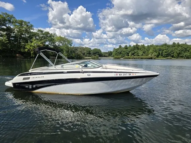 Slide: The Image of A 2003 Crownline 230 BR boat floats on a calm lake under a cloudy sky. - 26