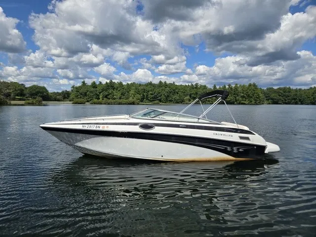 Slide: The Image of A 2003 Crownline 230 BR floats on a calm lake under a cloudy sky. - 23