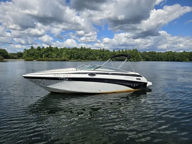 Slide: The Image of A 2003 Crownline 230 BR boat floats on a calm lake under a cloudy sky. - 22