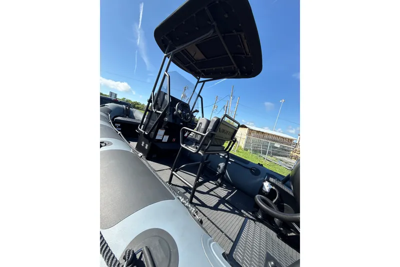 Slide: The Image of 2026 Highfield Patrol 540 boat interior with steering console and seating, under clear blue sky. - 1
