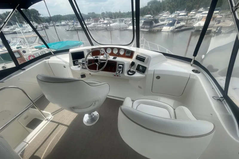 Slide: The Image of 2006 Silverton 34 Convertible yacht helm with white seating and marina view. - 34