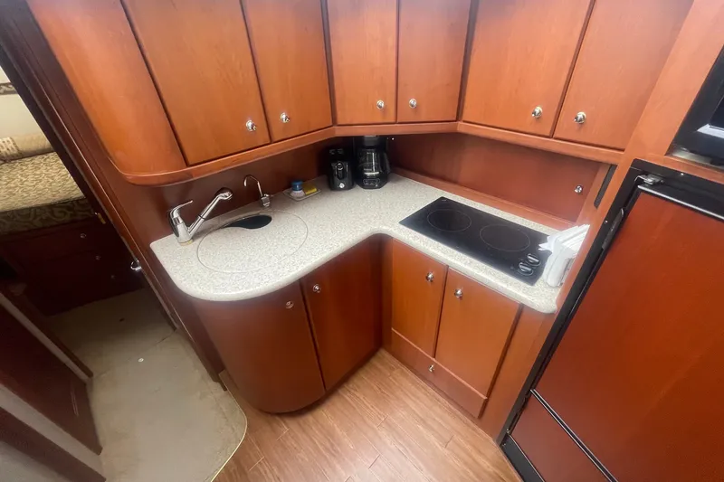 Slide: The Image of 2006 Silverton 34 Convertible yacht kitchen with wood cabinets, sink, and stovetop. - 49