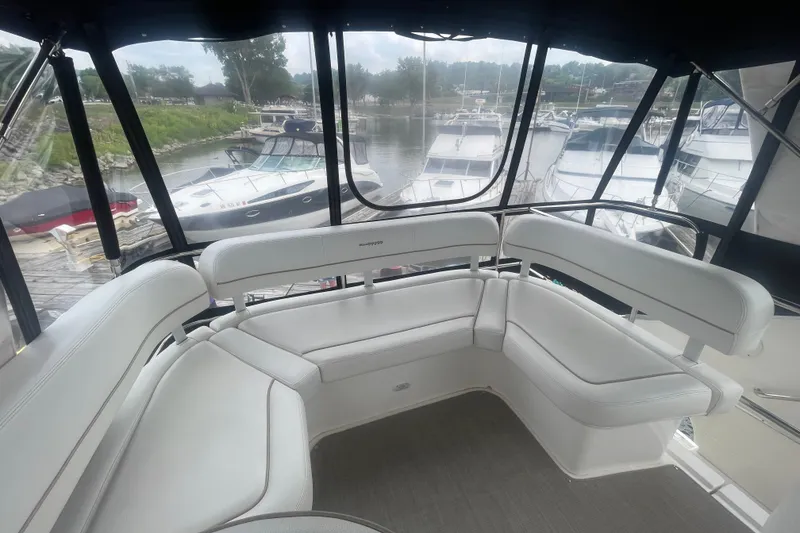 Slide: The Image of 2006 Silverton 34 Convertible yacht interior with white seating, docked at a marina. - 28