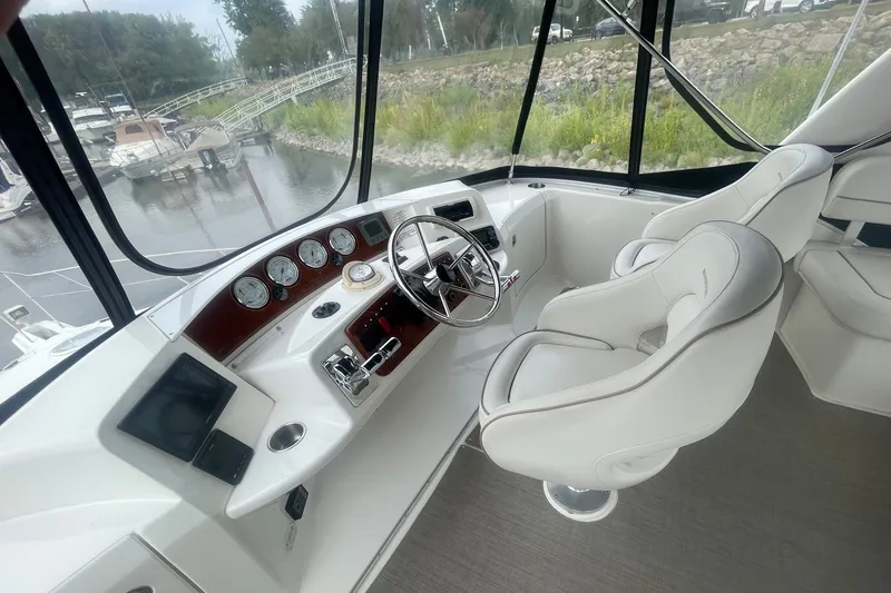 Slide: The Image of 2006 Silverton 34 Convertible helm with modern controls and plush seating, overlooking marina. - 31