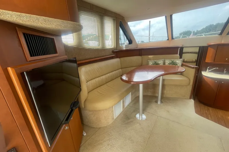 Slide: The Image of Interior of 2006 Silverton 34 Convertible yacht with beige seating and wooden table. - 42