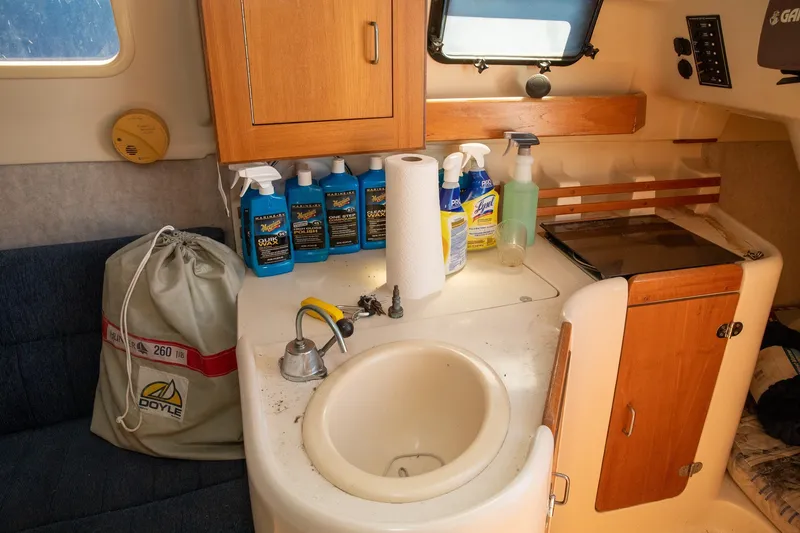 Slide: The Image of Interior of a 2004 Hunter 260 sailboat with cleaning supplies and compact sink area. - 13