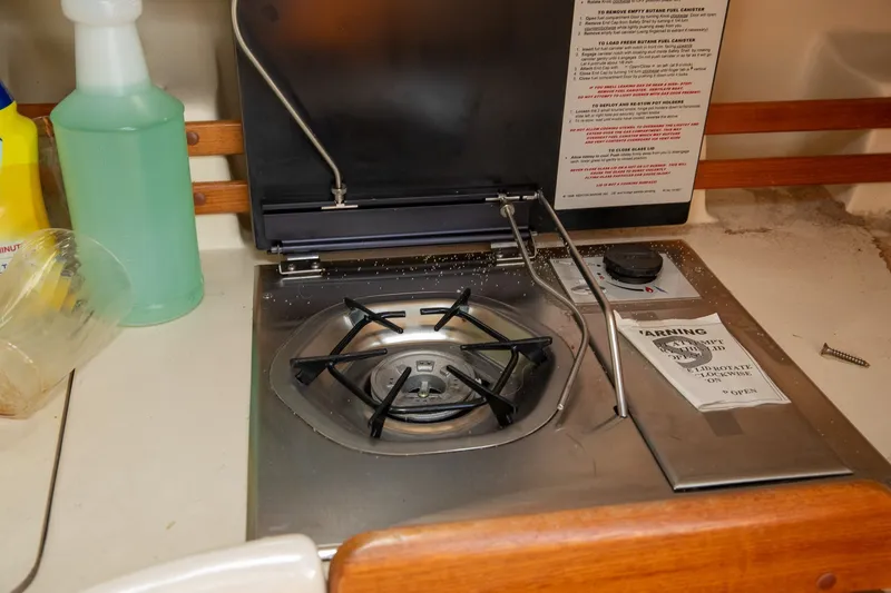 Slide: The Image of Compact stove in a 2004 Hunter 260 boat galley, with cleaning supplies nearby. - 16