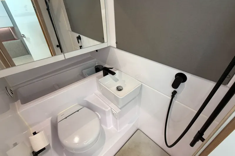 Slide: The Image of 2023 Axopar 45 XC Cross Cabin bathroom with compact sink, toilet, and shower. - 34