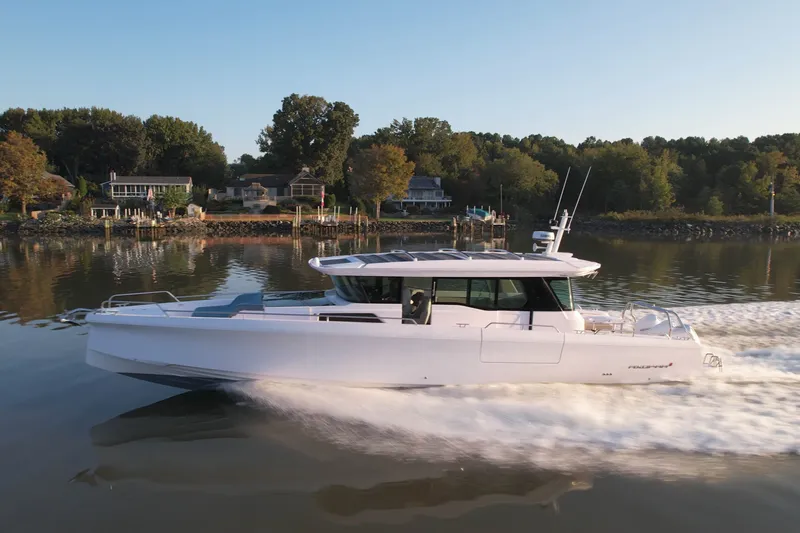 Slide: The Image of 2023 Axopar 45 XC Cross Cabin cruising on a serene lake near waterfront homes. - 39