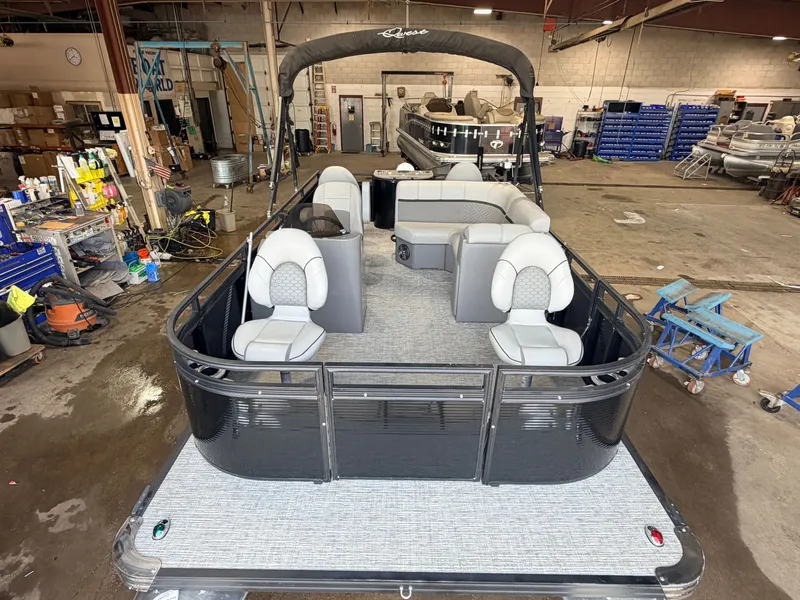 Slide: The Image of A modern pontoon boat with gray upholstery and black railing, parked in a workshop. - 9