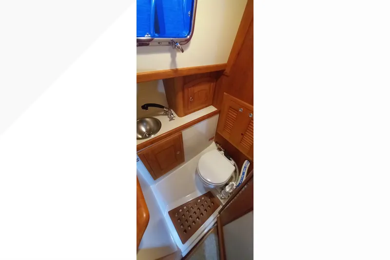 Slide: The Image of Interior of 2002 Pacific Seacraft Dana 24, featuring compact marine bathroom with wooden cabinetry. - 15