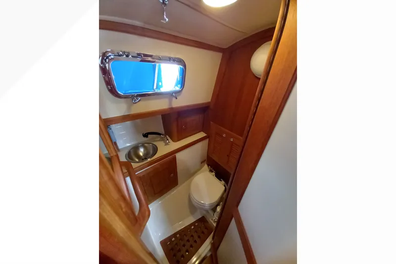 Slide: The Image of Interior of 2002 Pacific Seacraft Dana 24 sailboat bathroom with wooden cabinetry and porthole. - 43
