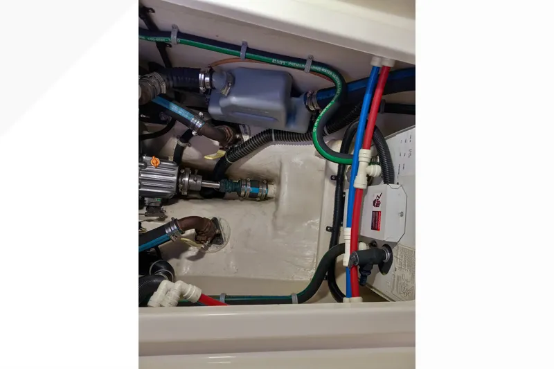 Slide: The Image of Engine compartment of a 2002 Pacific Seacraft Dana 24 sailboat, showcasing hoses and mechanical components. - 58