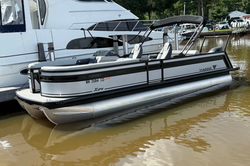 The Image of 2026 Viaggio X24 pontoon boat docked on calm water. - 2