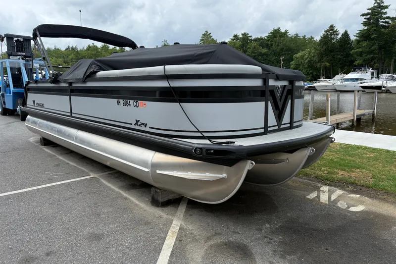 Slide: The Image of 2026 Viaggio X24 pontoon boat parked near a marina, covered and ready for transport. - 1