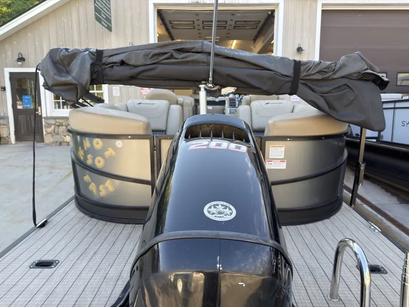 Slide: The Image of A 2019 Starcraft SLS 3 pontoon boat with a 200 HP engine, parked in front of a garage. - 26