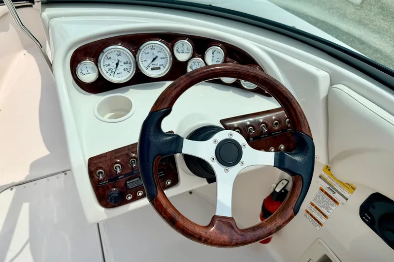 Slide: The Image of 2005 Starcraft 2100 IO RE Limited boat dashboard with wood-accented steering wheel and gauges. - 43