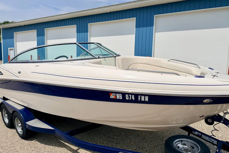 Slide: The Image of 2005 Starcraft 2100 IO RE Limited boat on trailer, parked near blue building. - 16