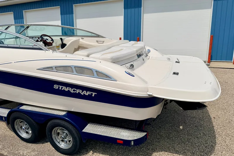 Slide: The Image of 2005 Starcraft 2100 IO RE Limited boat on trailer, parked near blue building. - 10