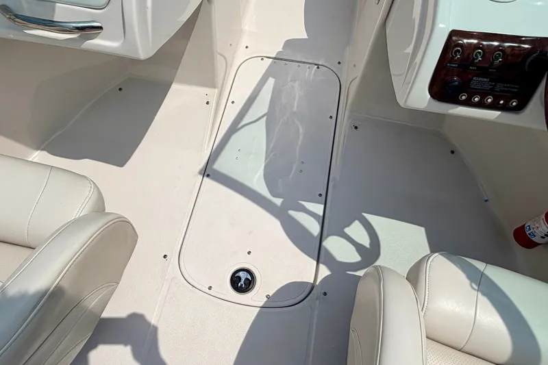 Slide: The Image of Interior of a 2005 Starcraft 2100 IO RE Limited boat, featuring white seating and control panel. - 56