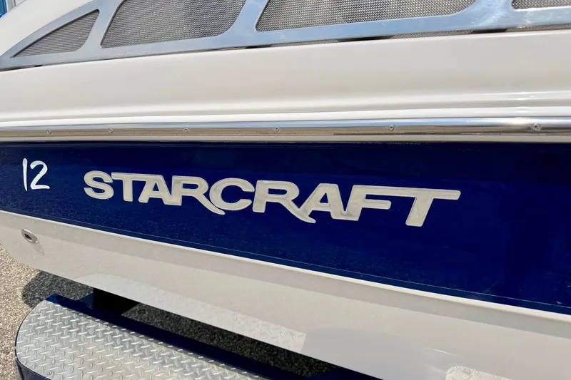 Slide: The Image of 2005 Starcraft 2100 IO RE Limited boat with blue and white exterior detailing. - 12