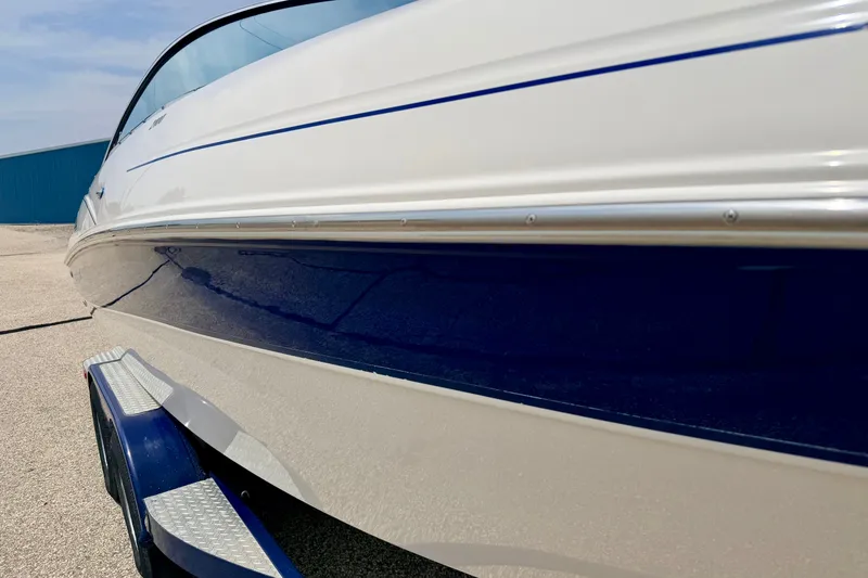 Slide: The Image of 2005 Starcraft 2100 IO RE Limited boat, white and blue exterior, parked on trailer. - 11