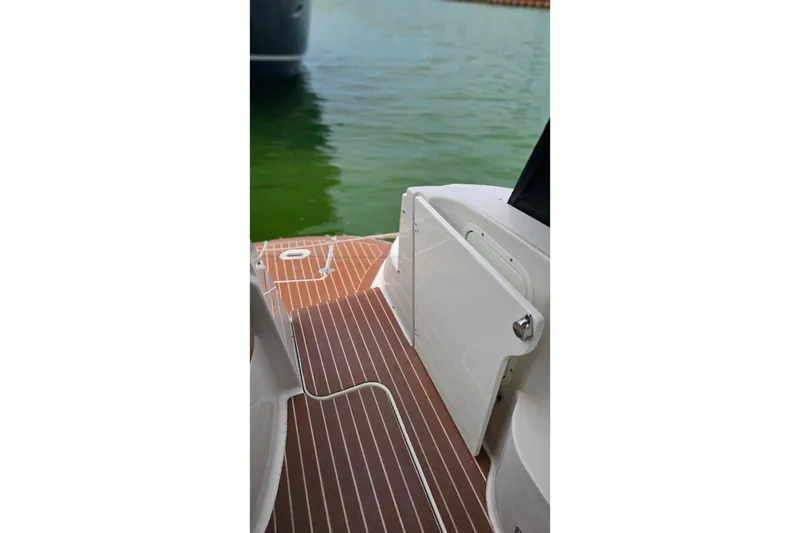 Slide: The Image of 2013 Four Winns V335 boat deck with wood finish, docked on calm green water. - 58