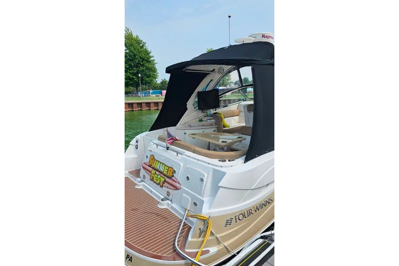 Slide: The Image of 2013 Four Winns V335 boat with canopy, docked near water, featuring "Summer Fest" sign. - 45