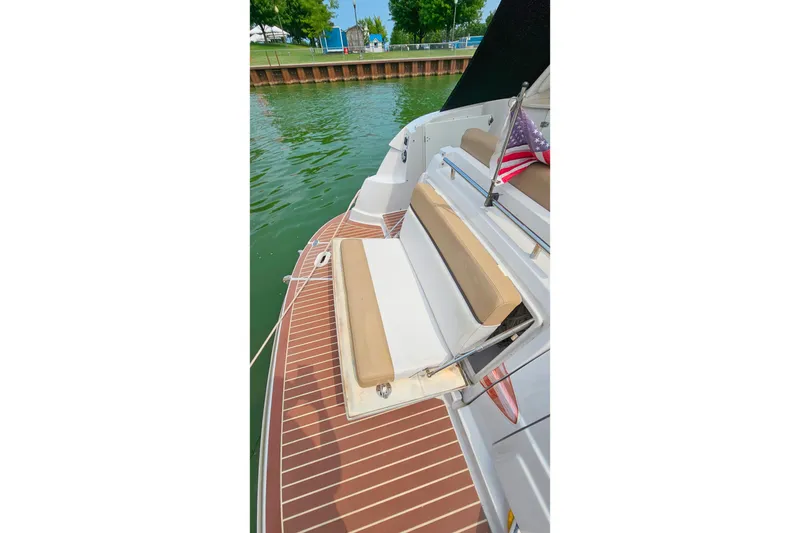 Slide: The Image of 2013 Four Winns V335 boat with cushioned seating and American flag on deck. - 52