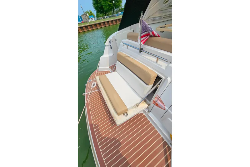 Slide: The Image of 2013 Four Winns V335 boat with cushioned seating and American flag on deck. - 55