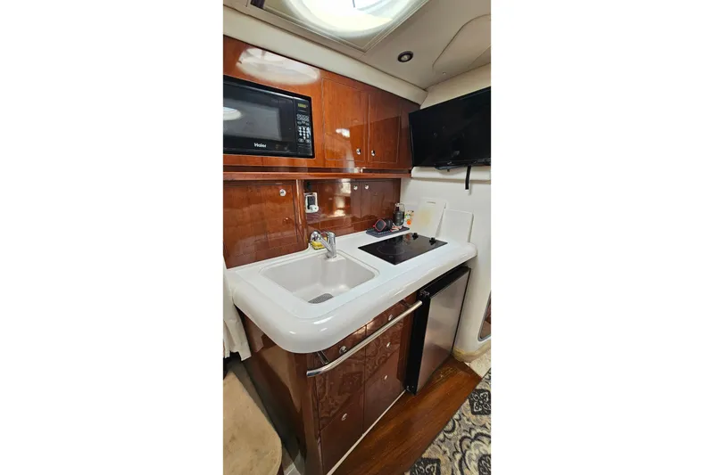 Slide: The Image of 2013 Four Winns V335 yacht kitchen with sink, stove, microwave, and fridge. - 12