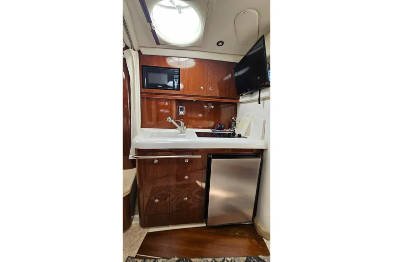 Slide: The Image of 2013 Four Winns V335 yacht interior kitchen with microwave, sink, and mini fridge. - 13