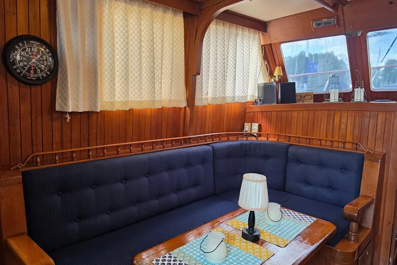 Slide: The Image of Cozy interior of a 1983 Monk 36 boat with wooden paneling and navy seating. - 12