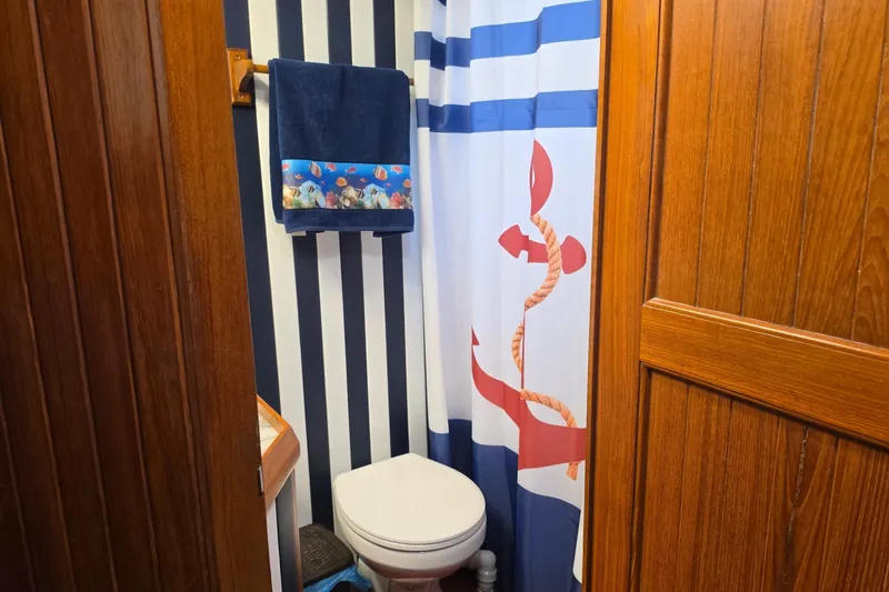 Slide: The Image of Nautical-themed bathroom in 1983 Monk 36 boat with striped walls and anchor shower curtain. - 17