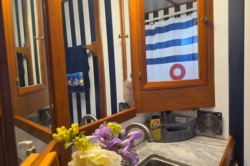 Slide: The Image of Bathroom vanity with wooden cabinets, striped shower curtain, and floral arrangement on marble countertop. - 18