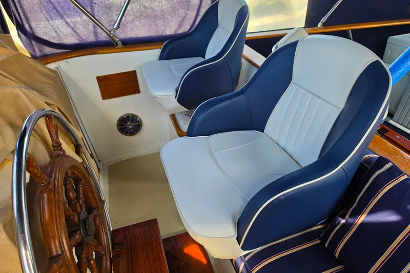 Slide: The Image of Captain's chairs and wooden helm on a 1983 Monk 36 boat. - 3