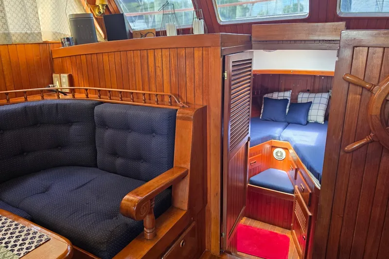 Slide: The Image of Cozy 1983 Monk 36 yacht interior with wooden paneling and blue cushioned seating. - 9