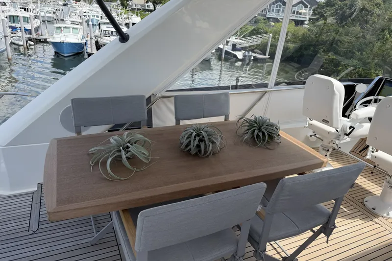 Slide: The Image of Luxurious 2023 Prestige 690 yacht deck with elegant dining setup and marina view. - 13