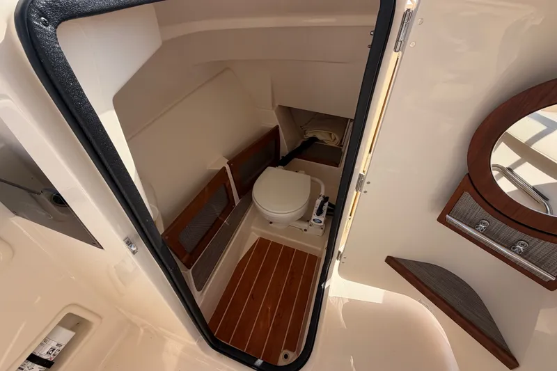 Slide: The Image of 2025 Grady-White Freedom 235 boat interior with compact marine toilet and wooden flooring. - 24
