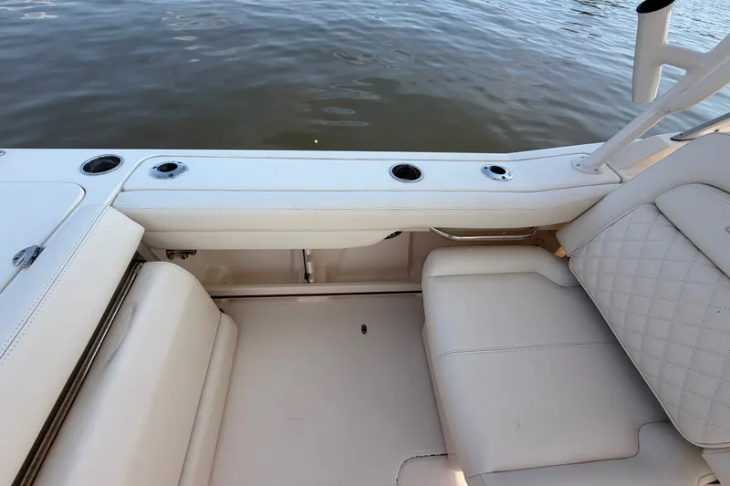 Slide: The Image of 2025 Grady-White Freedom 235 boat interior with white seating and cup holders by the water. - 31