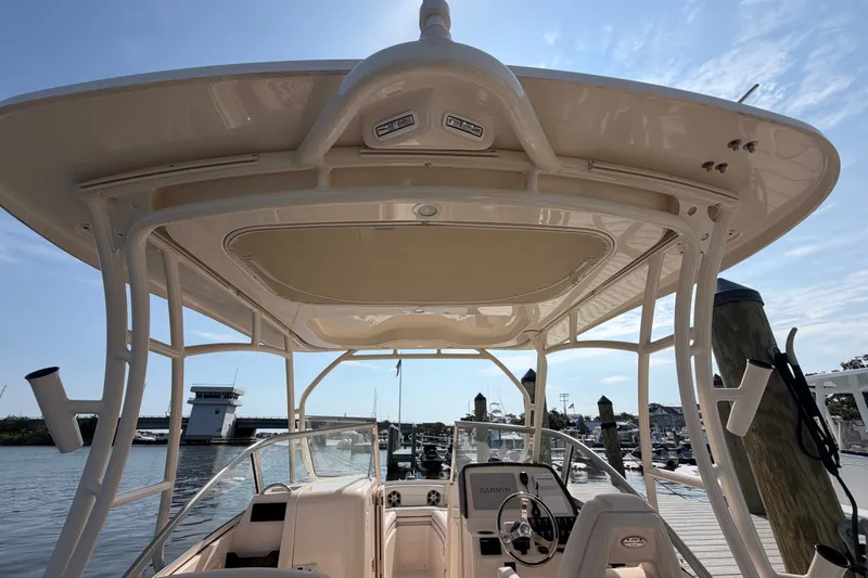 Slide: The Image of 2025 Grady-White Freedom 235 boat interior with helm, docked at marina under clear sky. - 29
