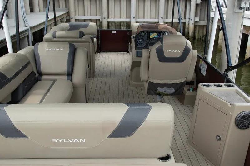 Slide: The Image of 2023 Sylvan L5 DLZ Bar pontoon boat interior with beige seating and helm. - 5