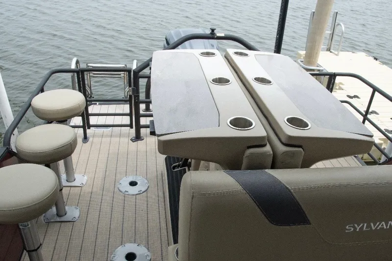 Slide: The Image of 2023 Sylvan L5 DLZ Bar pontoon boat with bar stools and table on deck. - 7
