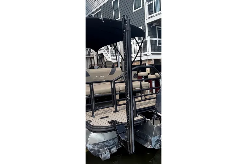 Slide: The Image of 2023 Sylvan L5 DLZ Bar pontoon boat docked near waterfront homes. - 8