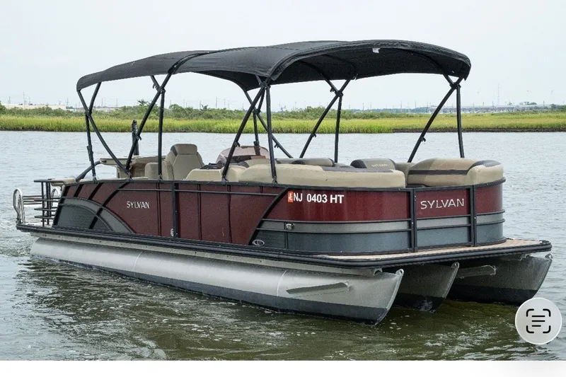 The Image of 2023 Sylvan L5 DLZ Bar pontoon boat on water, featuring a sleek design and canopy. - 0